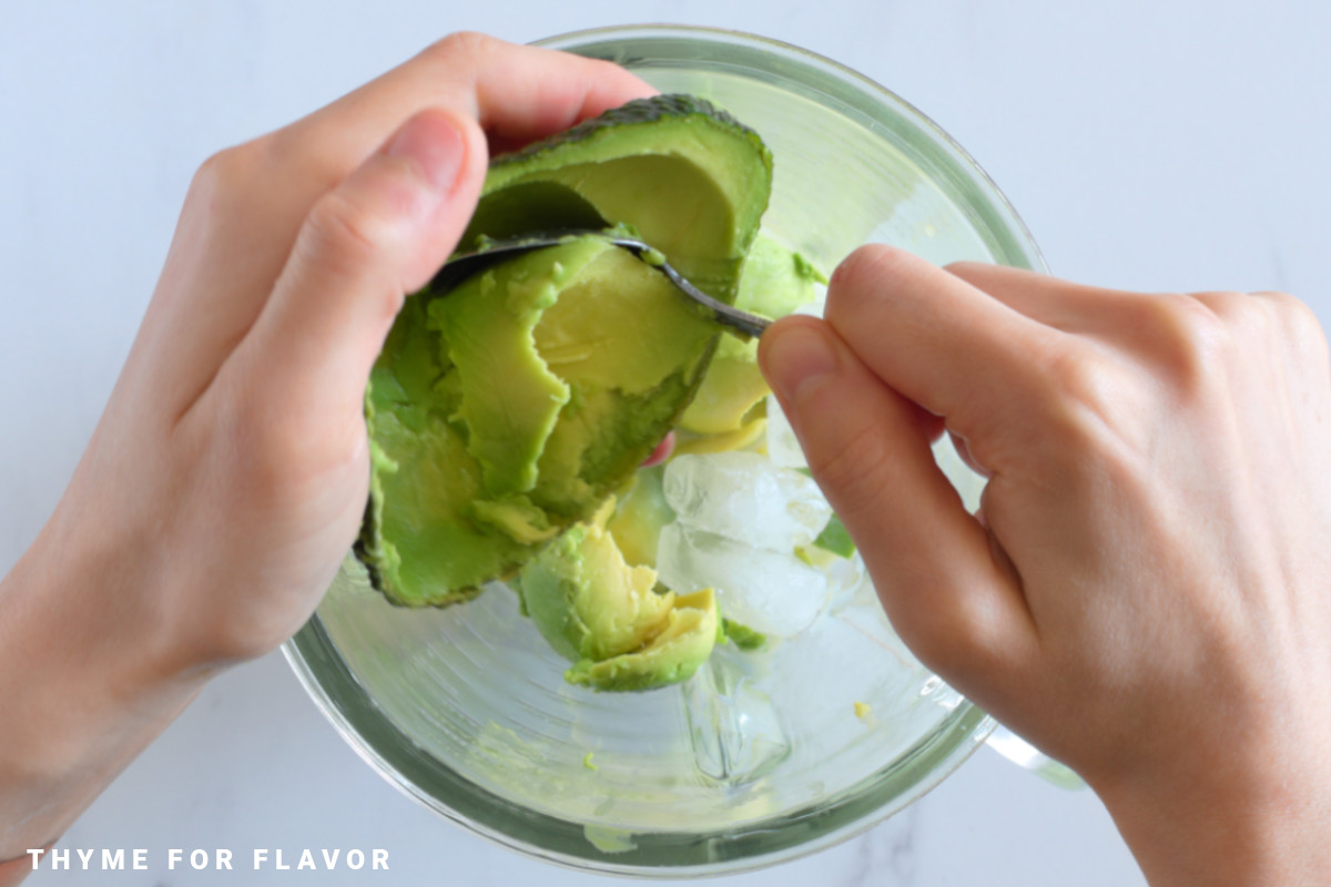 Putting avocado flesh into a blender.