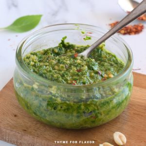 A close up image of Thai basil pesto in a glass container.