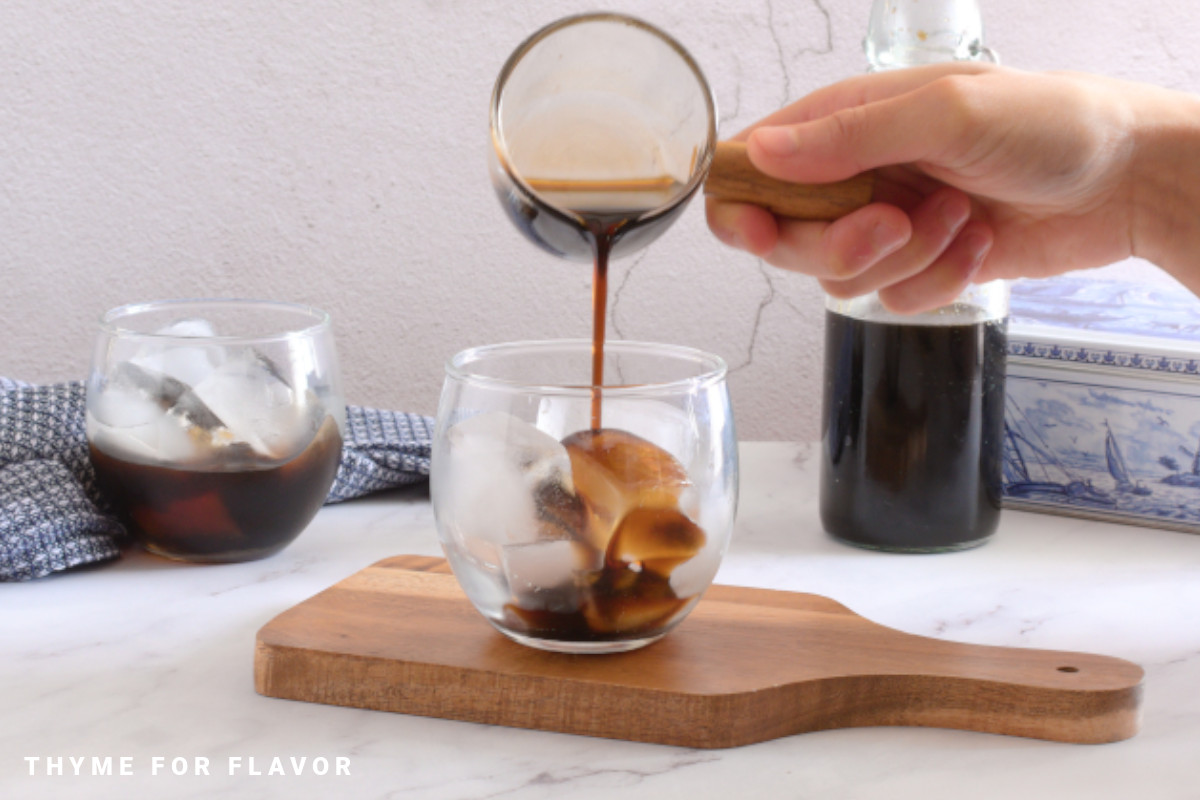 Brown sugar syrup for boba being poured over a glass full of ice.