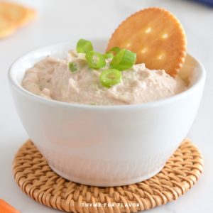 Tuna dip in a small white bowl, with a cracker on top.