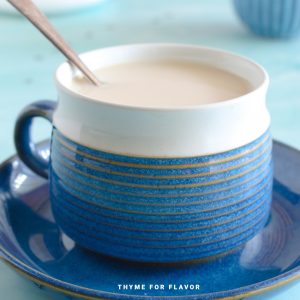 Assam milk tea in a blue mug with a spoon.