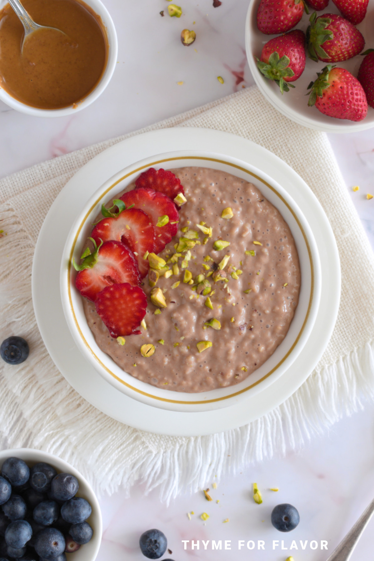 Porridge with Nutella in a white bowl with chopped pistachios and strawberries on top.