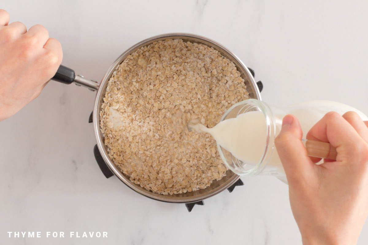Pouring milk into a saucepan with oats.