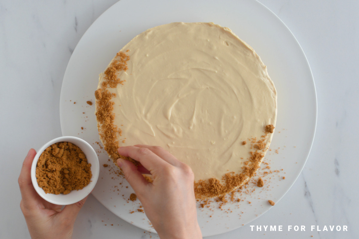 Placing biscuit crumbs on top of the lotus cheesecake.