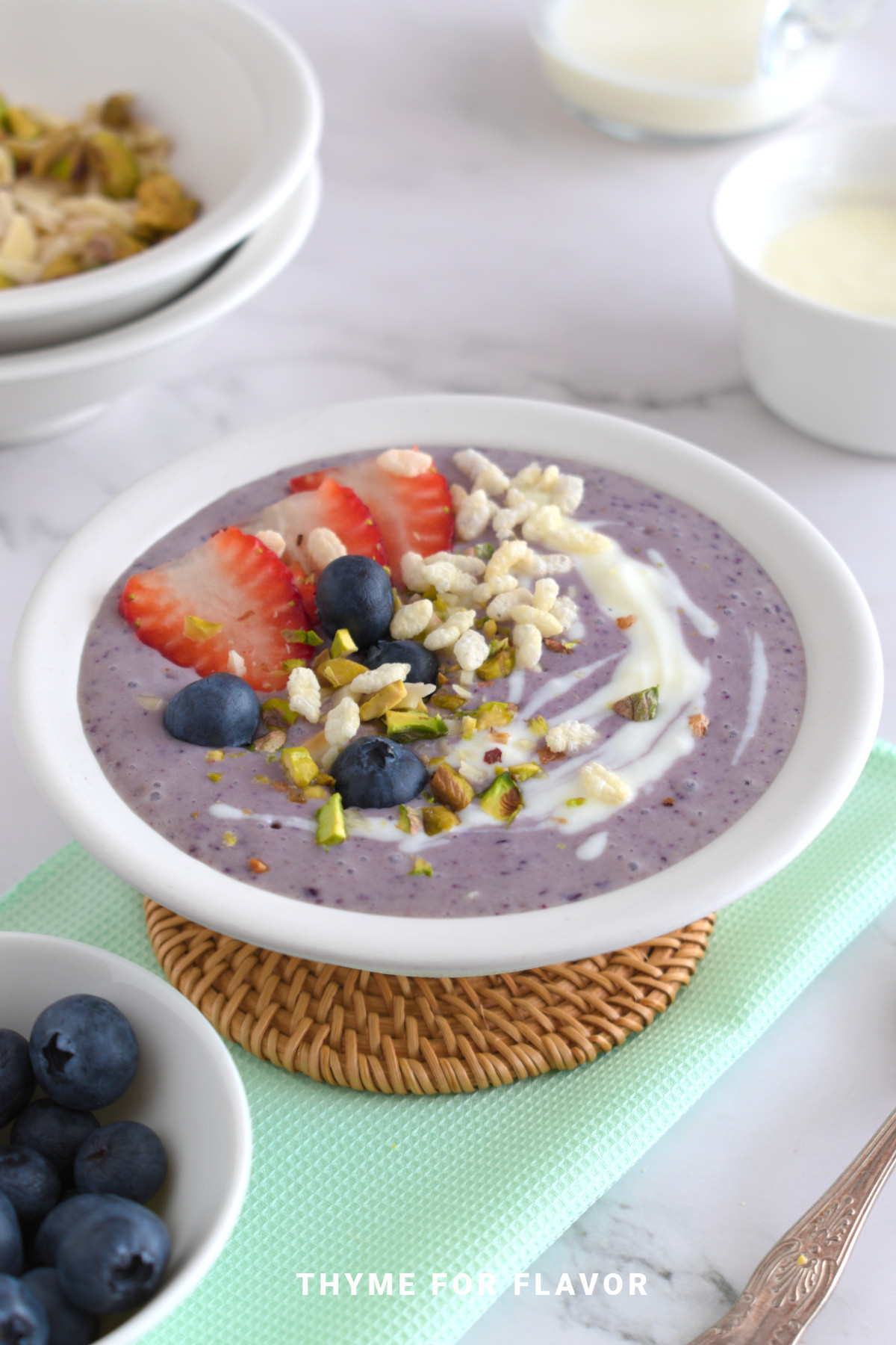 Purple smoothie bowl topped with fresh fruit, puffed rice, yogurt, and pistachios.
