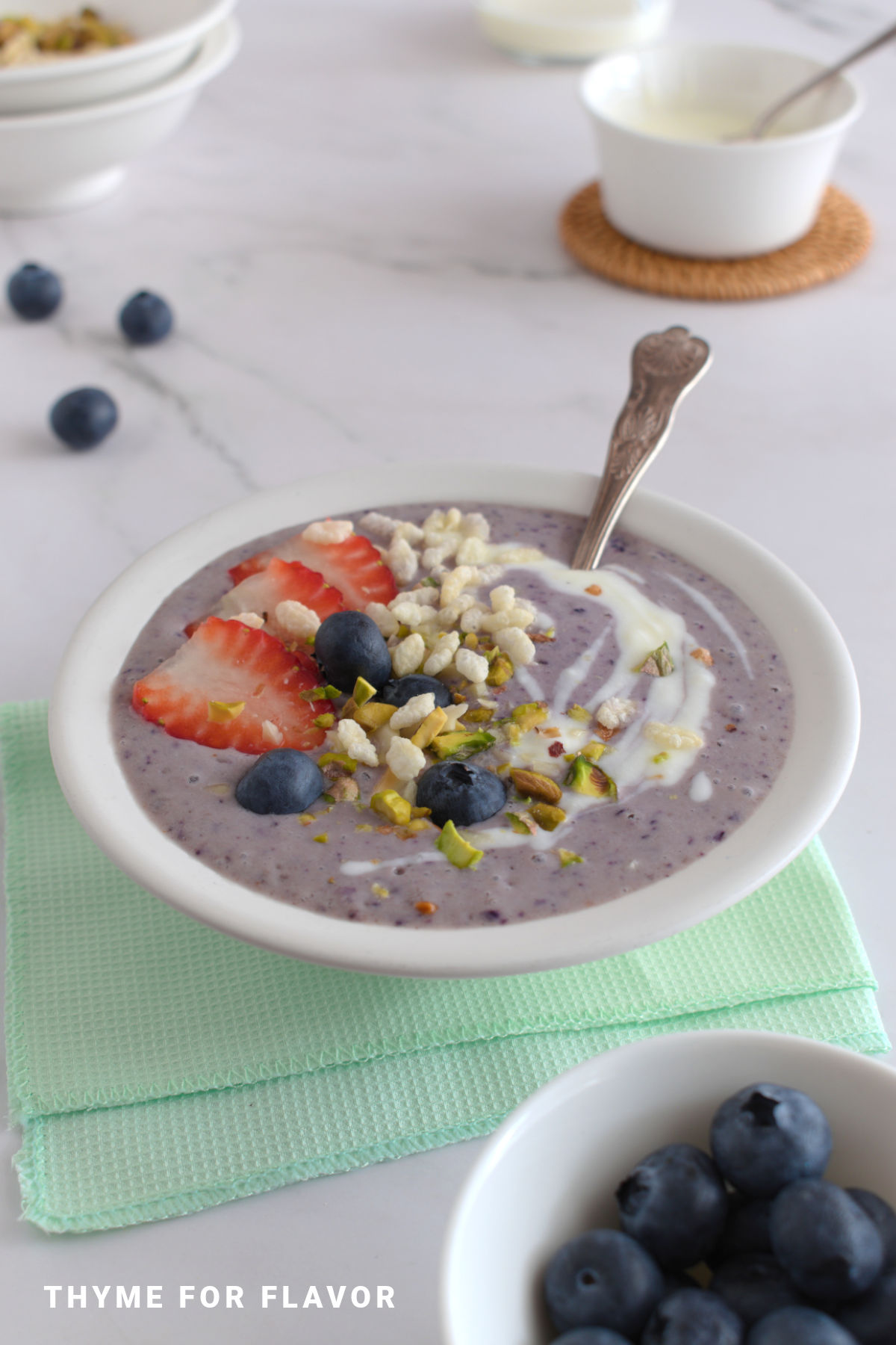 Purple smoothie bowl in a white bowl on a green napkin.