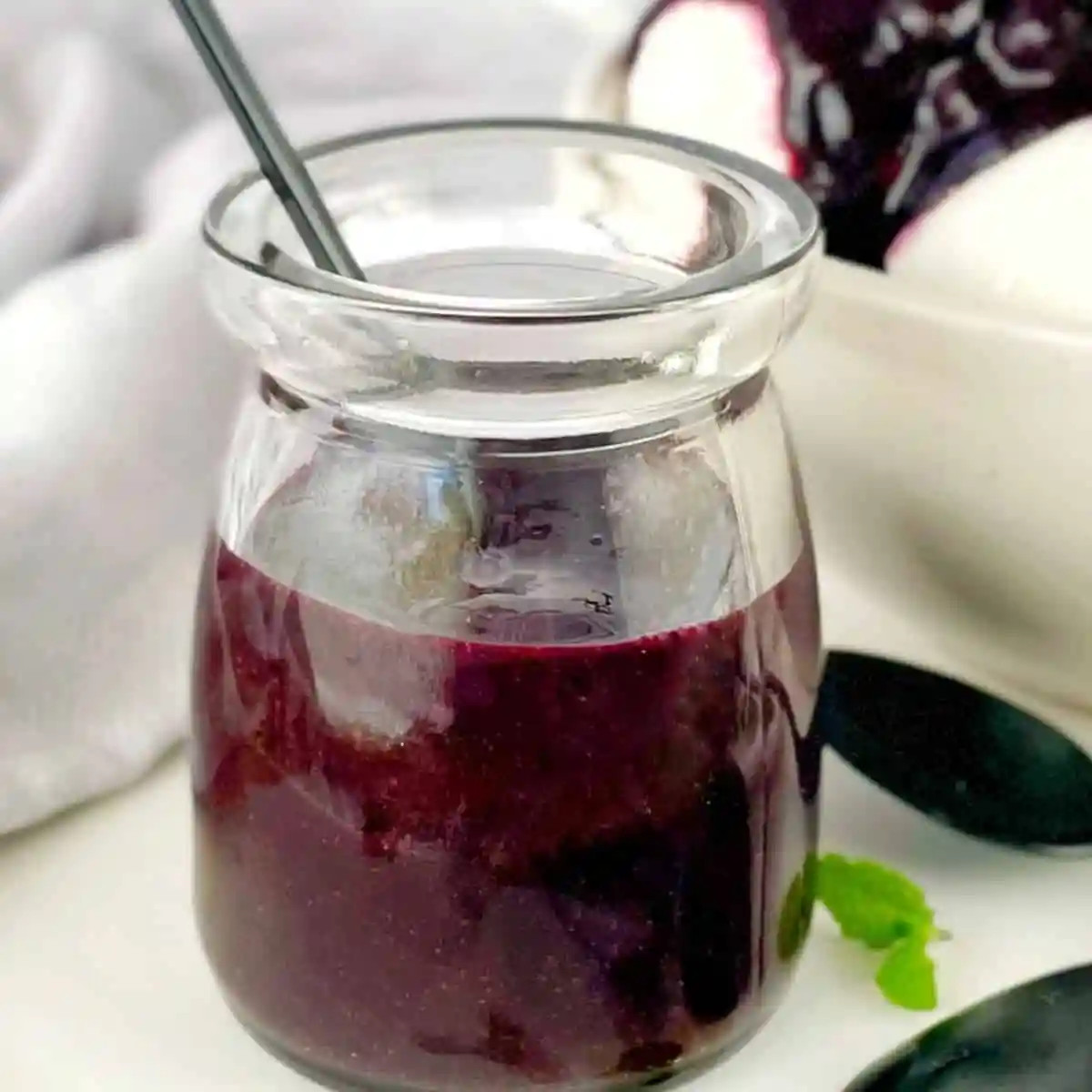 Blueberry coulis in a glass jar.