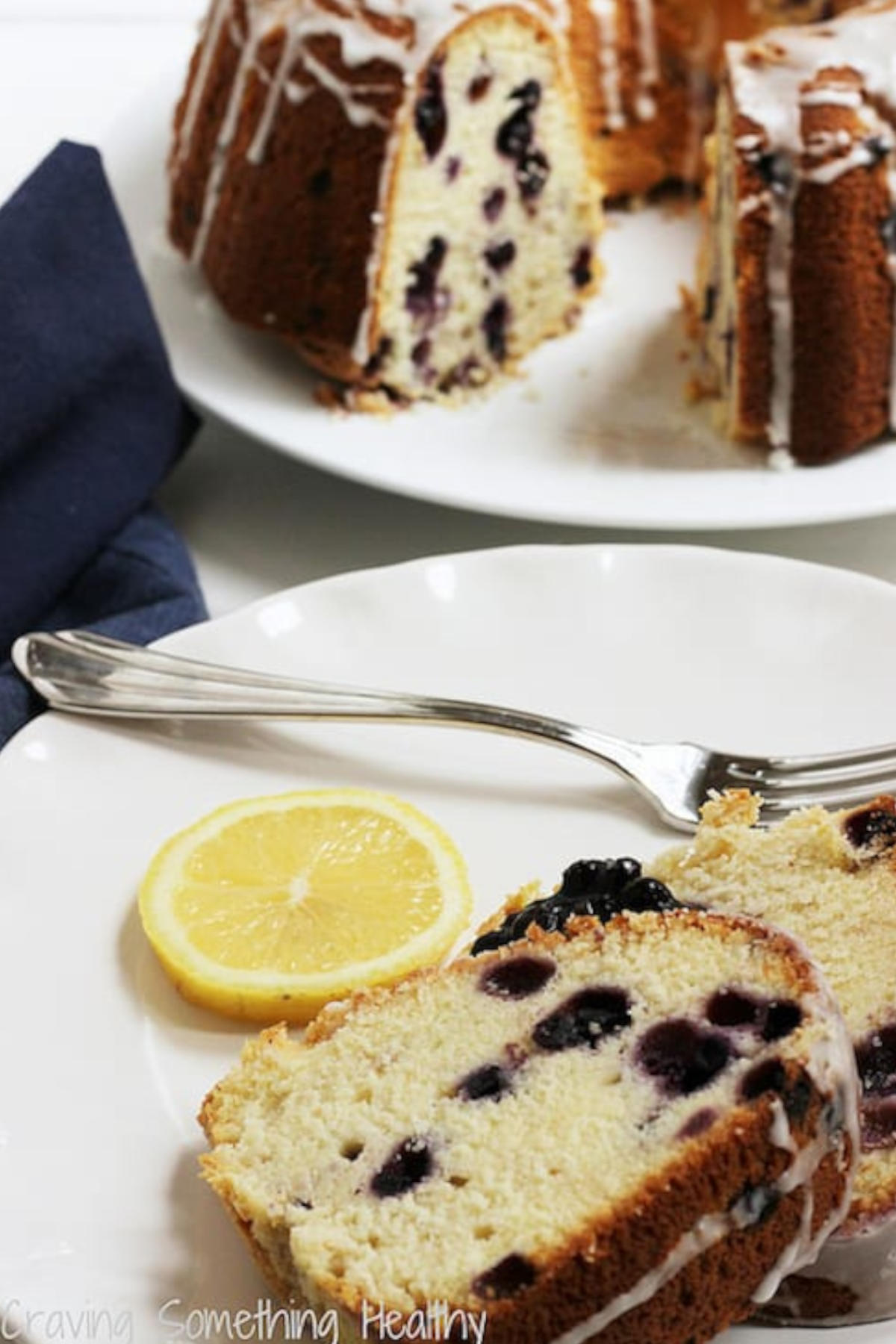 Slices of blueberry lemon pound cake on a plate with a slice of lemon and a fork.