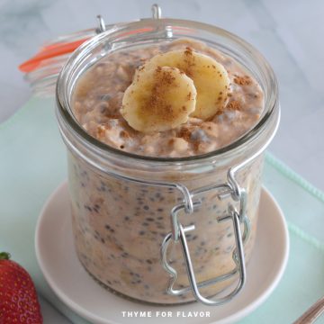 Close up image of cinnamon banana overnight oats in a glass jar on a white plate.
