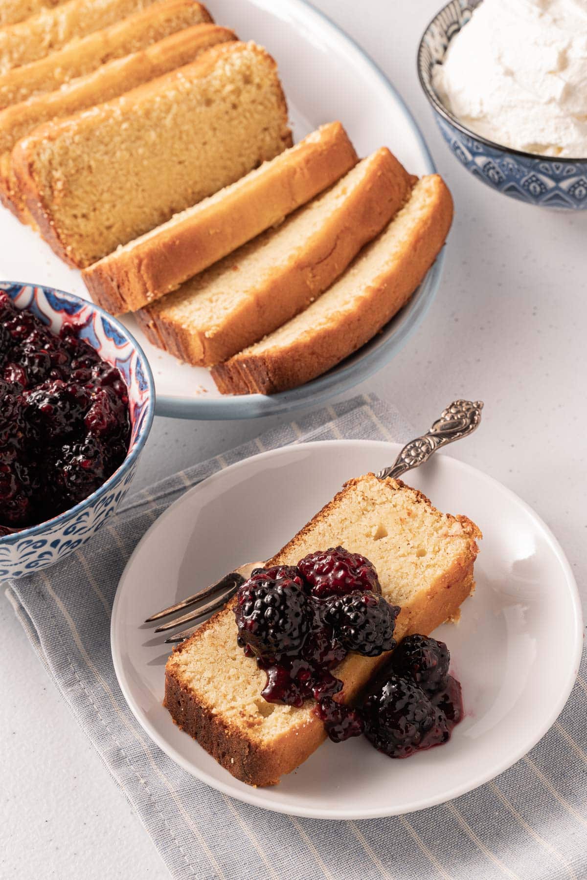 Blackberry compote on a slice of cake in a white bowl.