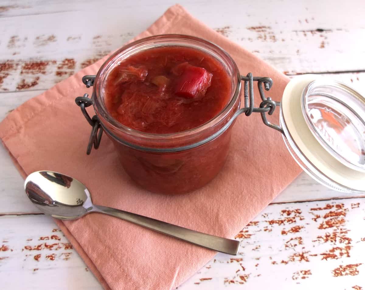 Rhubarb compote in a jar on a pink napkin.