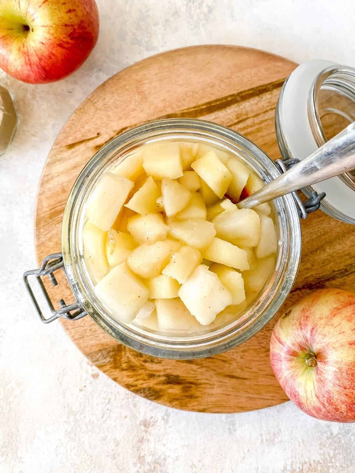 Apple and pear compote in a glass jar with a spoon.