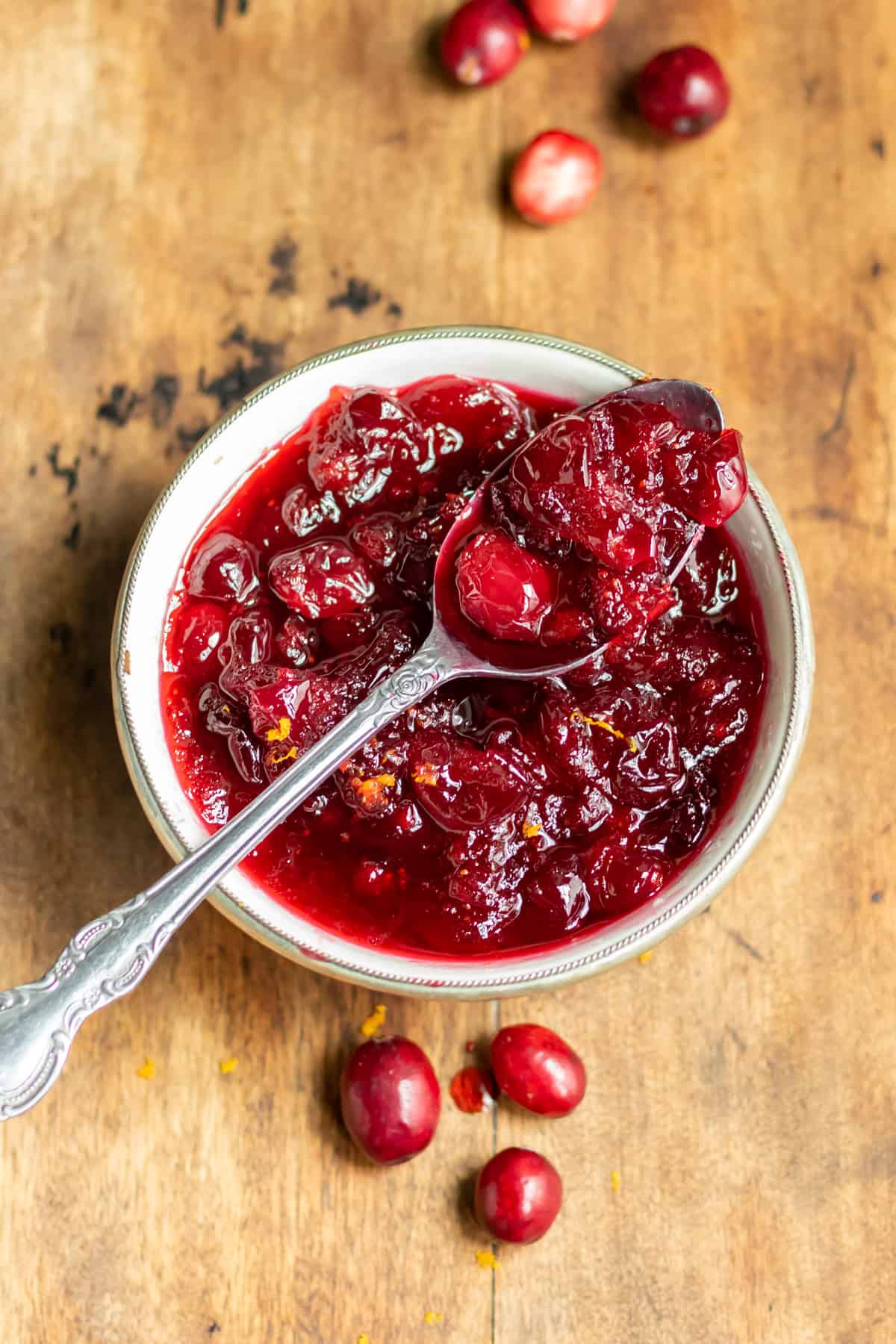 Cranberry compote in a bowl with a spoon resting on top of the bowl.