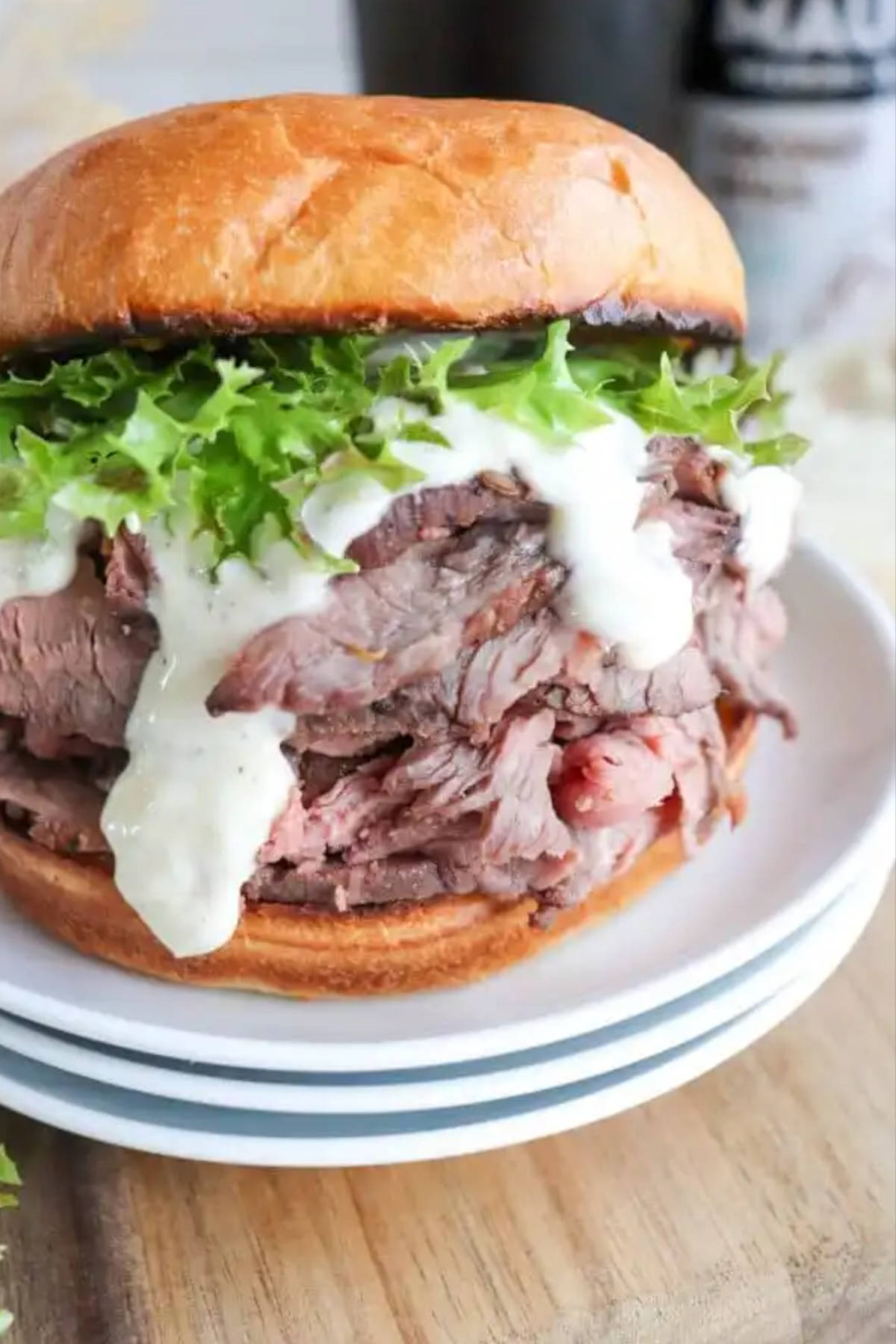 Close up image of a roast beef sandwich on a stack of plates.