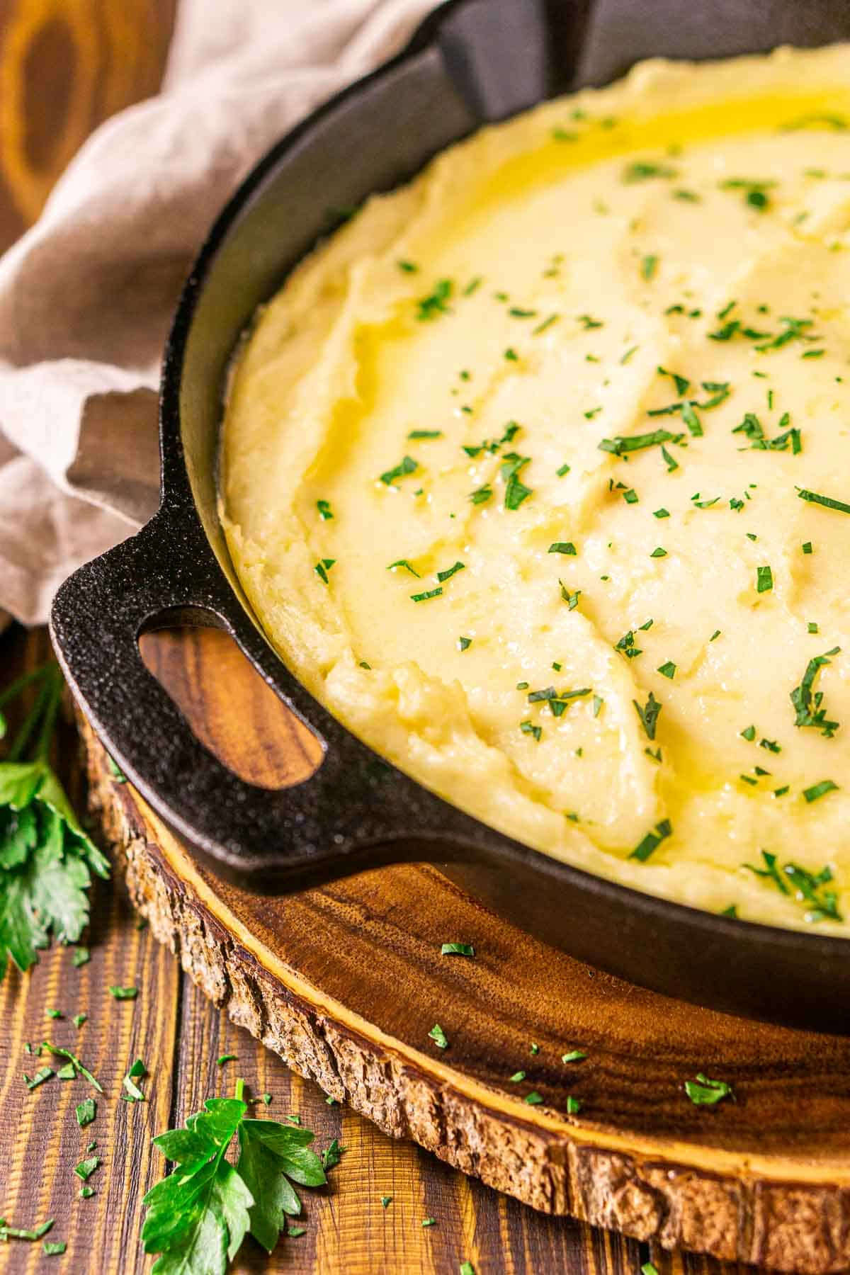 Mash potatoes with parsley leaves on top in a black skillet.