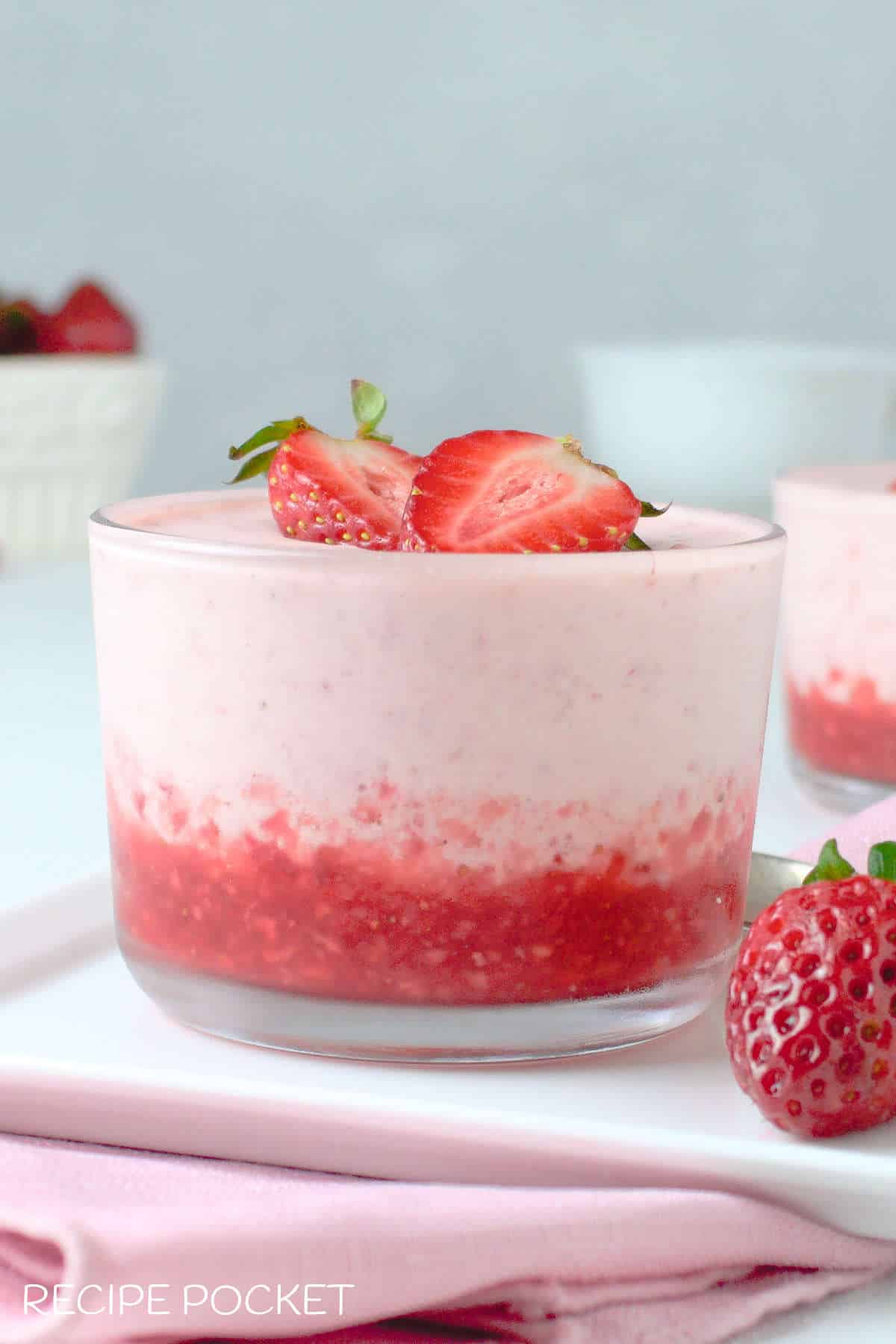 Strawberry fool in a glass with sliced strawberries on top.