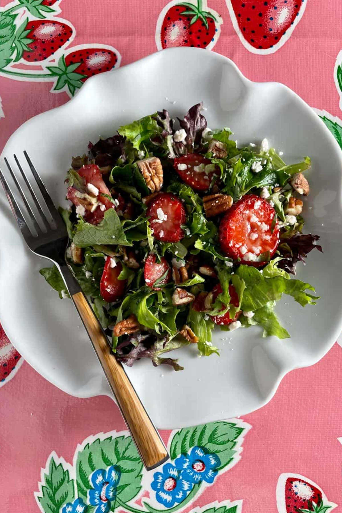 A plate of strawberry salad with a fork.