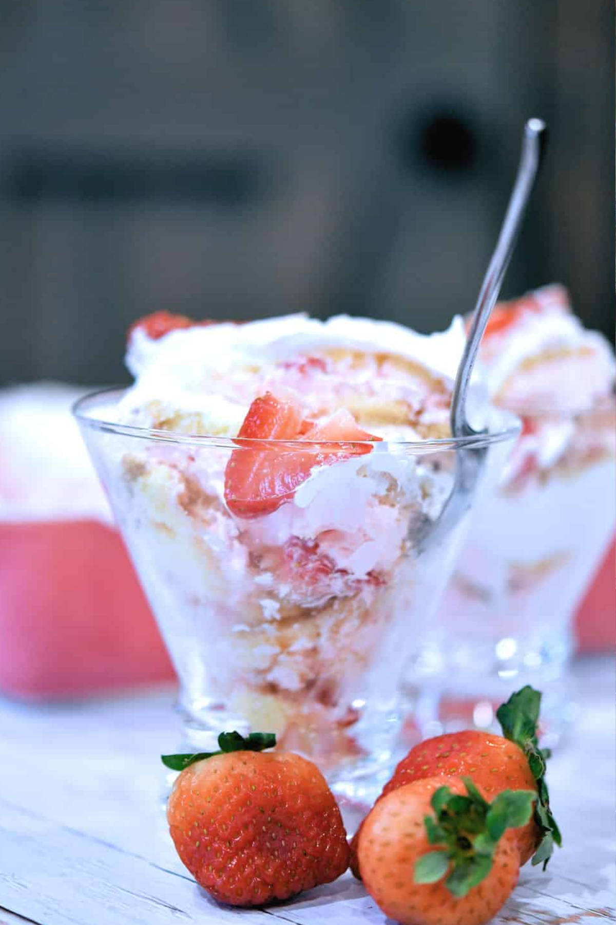 Close up image of a strawberry tiramisu in a glass with a spoon.