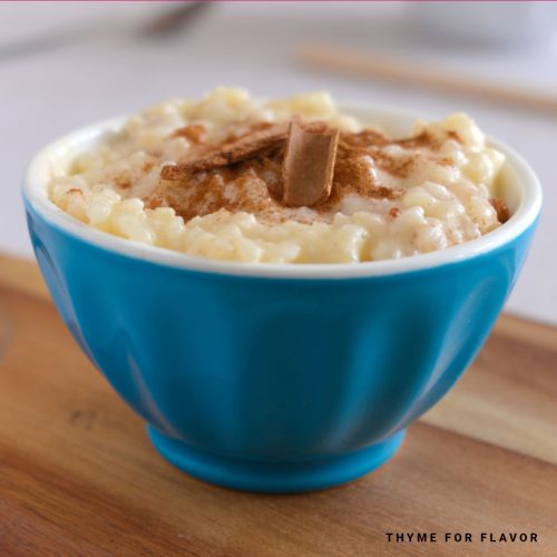 Close up image of arroz doce with cinnamon on top in a blue bowl.