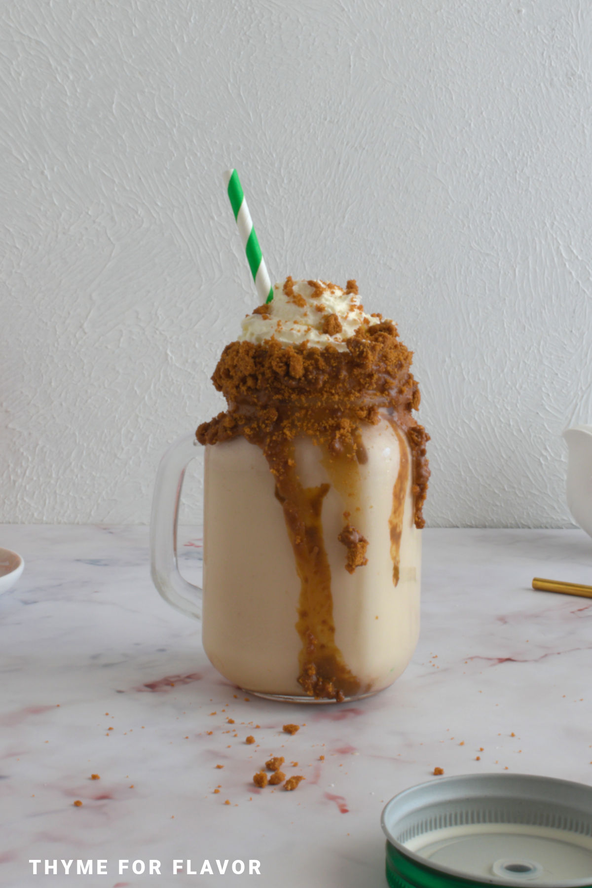 Biscoff milkshake in a glass with a straw.