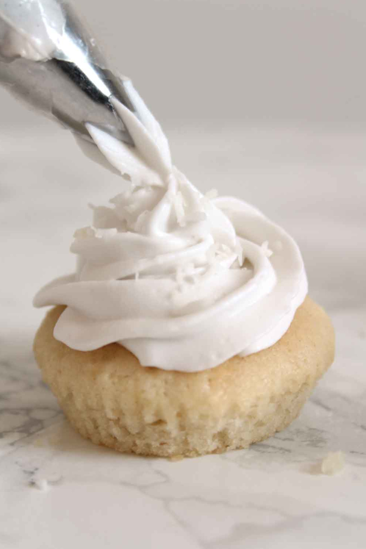 Coconut whipped cream being piped on a muffin.