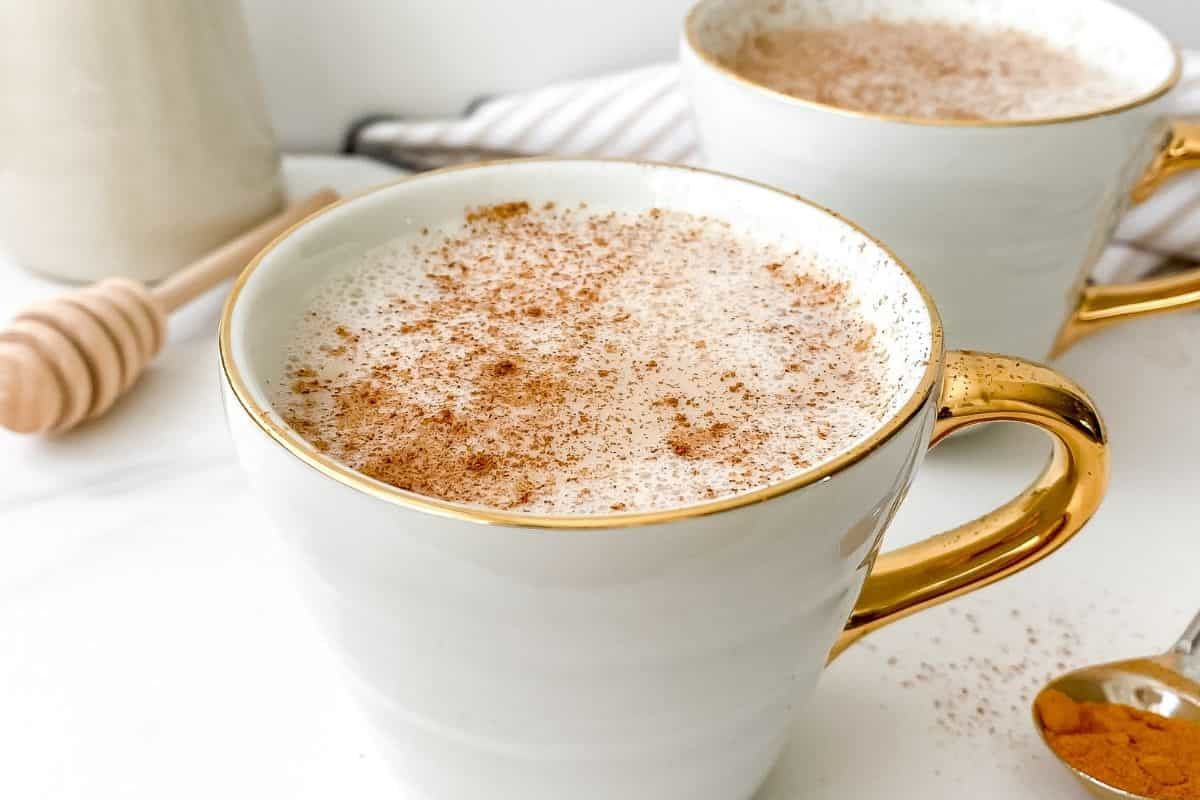 Close up image of honey ginger warm milk in a white mug.